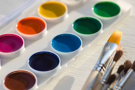 Colorful new watercolor paint palette and brushes. Selective focus on yellow brush.の写真素材