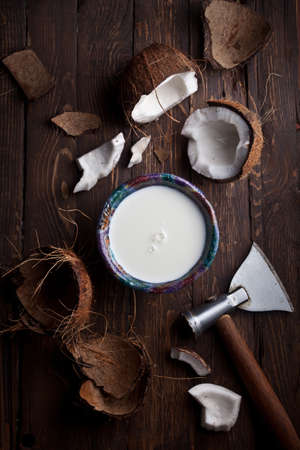 organic coconut milk with broken coconuts on rustic wooden table, nobody