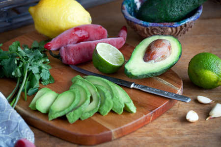 cooking mexican food  guacamole - avocado, lime, lemon, pepper, garlic and cilantro on a wood table....