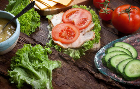bacon sandwich with fresh tomatoes, cheese, lettuce salad leaves, cucumber and sauce, on wooden rustic table background, nobodyの写真素材