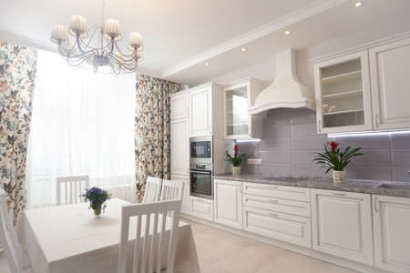 photo of empty minimalistic interior background, kitchen in modern apartment with big window, curtain, table, chairs, counter, equipment and flowers on table, nobody, with copy space, horizontalの写真素材