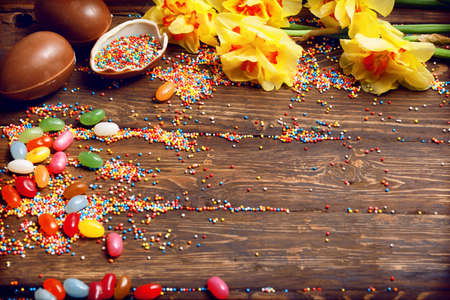 Easter empty background with Easter chocolate eggs, candies and spring flowers. Top view with copy space.の写真素材