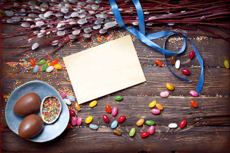 Easter empty background with Easter chocolate eggs, candies and spring flowers. Top view with copy space.の写真素材