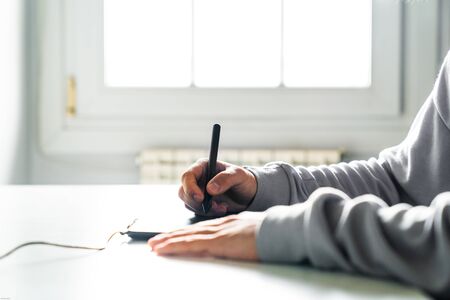 Young man designer working using graphics tablet at home office