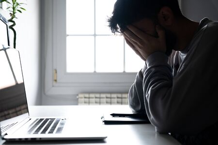 Young man tired of working from home with the computerの写真素材