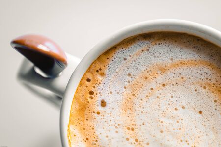 Zenithal view of a very creamy coffee cup with its ceramic spoonの写真素材