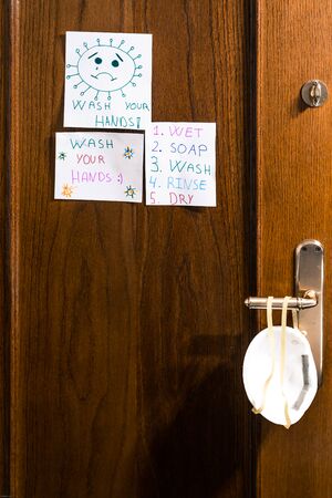 Door of the bathroom with drawings made by a child of positive messages for the coronavirus and with a mask.の写真素材