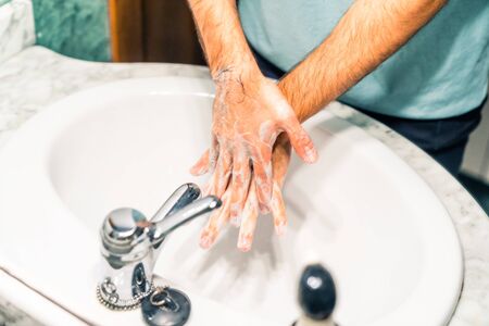 Washing your hands thoroughly with disinfectant soap at the sink to prevent coronavirus infection. Reflection of a mirror.の写真素材