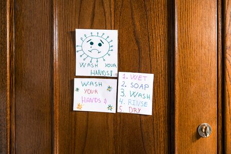 Drawings by a child of positive messages for the coronavirus hanging on the bathroom door. Wash your hands.の写真素材