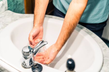 Washing your hands at a sink to prevent coronavirus infection. Tap on. Reflection of a mirror.の写真素材