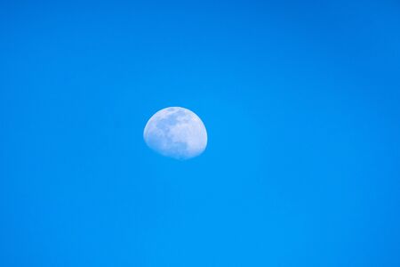 Blurred moon in the blue sky of a sunny day. Moon with the blue sky of day.