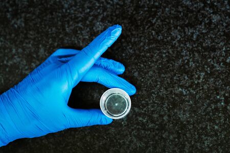 Hand with a blue latex glove holding a measuring cup.の写真素材