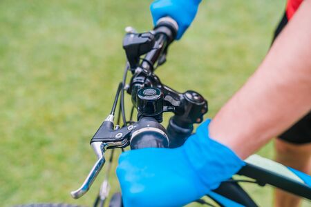 Person cycling through the park with blue latex gloves as a coronavirus prevention measure.の写真素材