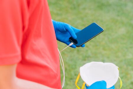 Person who plays sports by listening to music with a mobile phone with a mask and blue latex gloves because of the preventive measures needed for the coronavirus.の写真素材