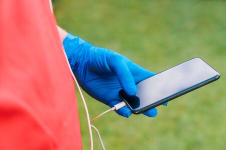 Hand of a person who does sport listening to music with a mobile phone with blue latex gloves because of the prevention measures needed for the coronavirus.の写真素材