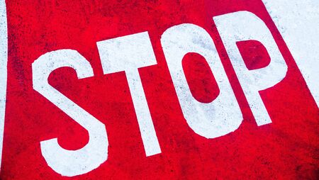 Diagonal stop signal painted on the red asphalt of a road.の写真素材