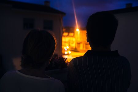 Stock photo of a mature couple worriedly watching an ambulance from their home at night.の写真素材