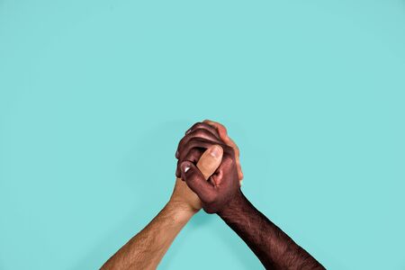 Multicultural hands united calling for freedom and equality on a blue background. African black hand and caucasian white hand together calling for stop racism.の写真素材