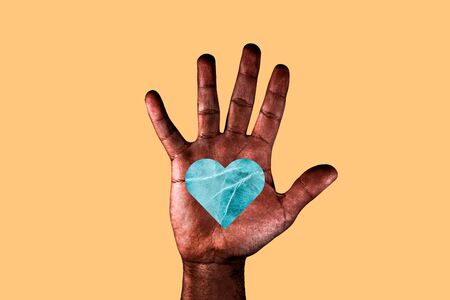Open palm of a African American man with a heart drawn asking for the stop of racism. Black hand with a blue heart isolated on a orange background.の写真素材