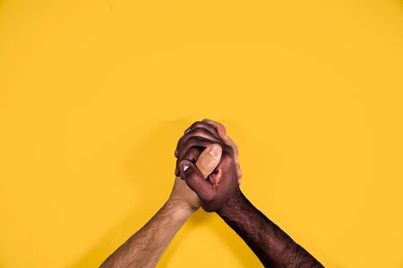 Multicultural hands united calling for freedom and equality on a yellow background. African and caucasian hands together calling for stop racism.の写真素材