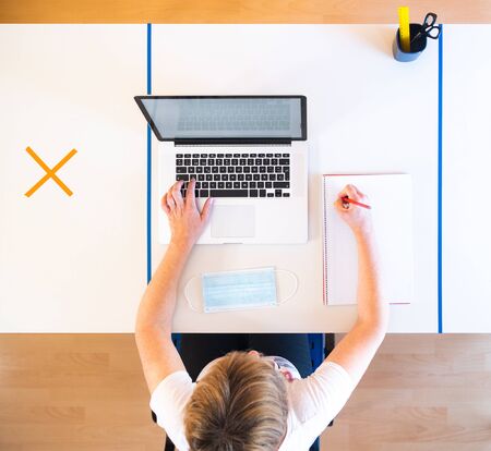 Business woman working alone with a laptop in a office workspace with social distancing measures adapted to the new normality to avoid a resurgence of the coronavirus.の写真素材