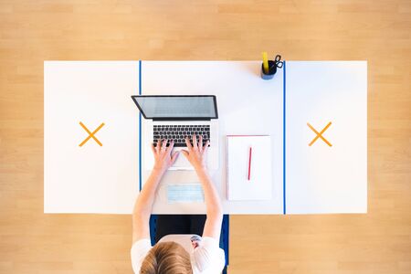 Top view of a business woman working alone with a laptop in the office to ensure social distancing measures to prevent the spread of the coronavirus.の写真素材