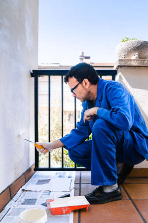 Man painting the white wall of the house terrace. Concept of painting and reforming the corners of the house.の写真素材