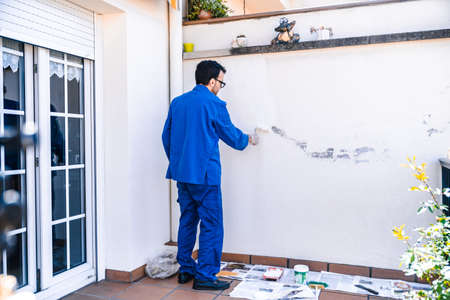 Man painting the white wall of the house terrace. Concept of painting and reforming the corners of the house.の写真素材