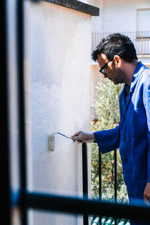 Man painting the white wall of the house terrace. Concept of painting and reforming the corners of the house.の写真素材