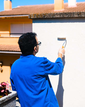 Man painting the white wall of the house terrace outside. Concept of painting and reforming the corners of the house.の写真素材