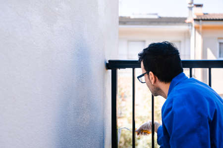 Man painting the white wall of the house terrace outside. Concept of painting and reforming the corners of the house.の写真素材