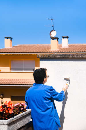 Person painting the white wall of the house terrace. Concept of painting and reforming the corners of the house.の写真素材