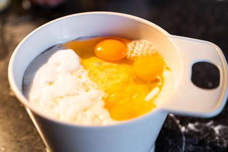 White recipient full of flour and eggs to make a cooking recipe. Preparation of a homemade cake at home.の写真素材