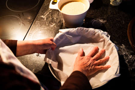 Woman preparing the paper for the cake container. Preparing a homemade cake at home in the evening...