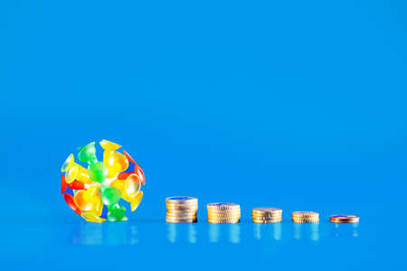 Isolated virus with different coins and money on a blue background. Covid-19 crisis. Economic crisis caused by coronavirus.の写真素材