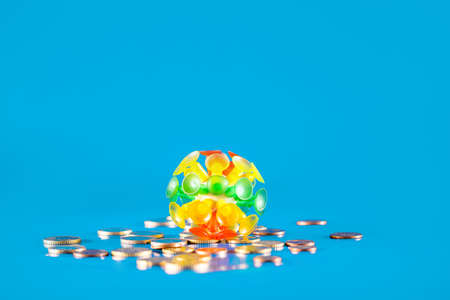 Virus knocking down a stack of different coins and money on a blue background. Covid-19 crisis concept. Economic crisis caused by coronavirus.の写真素材