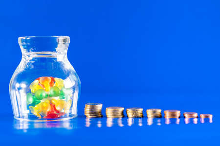 Solution for coronavirus crisis. Isolated virus with a stack of different coins and money on a blue...