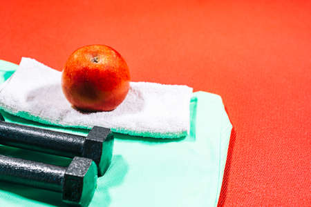 Attributes of a healthy lifestyle: apple, sport equipment, sports shirt, hand weights. Tools for fitness at home.の写真素材