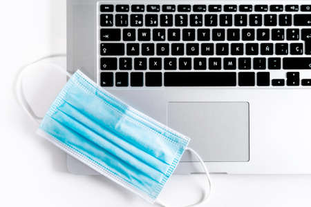Medical face mask on top of a laptop computer.の写真素材