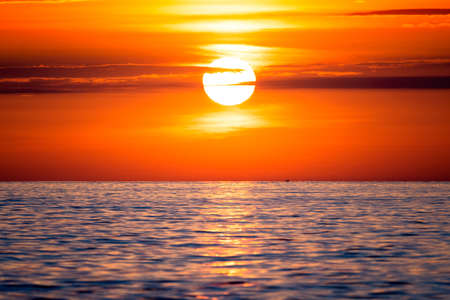 Beautiful sunrise or sunset on the sea with a small boat in the background. Background of a...