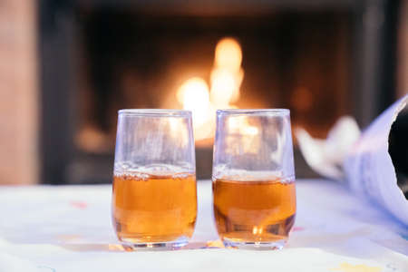 Two glasses with wine or "moscatell, moscatel" liquor with the fire of fireplace at the bottom. Celebrating "Castanyada, CastaÃ±ada" typical dish and tradition of Catalonia, Spain, in All Saints Day.の写真素材