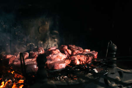 Grilled meat in the fireplace of his home. Raw beef on a barbecue grill with the coals underneath.の写真素材