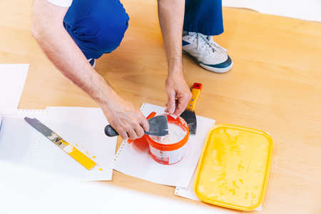 Painter man at work preparing the putty to paint the wall, top view, anonymous person.の写真素材