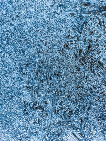 Ice texture. Blue winter background with water frozen by the cold. Vertical natural abstract background to use as a wallpaper or for your designs. Wintry.の写真素材