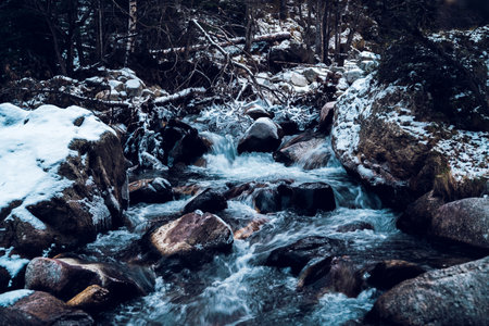 River in snowy and frozen mountain landscape. Frosty winter stream in mountains. Christmas time and vacations, beautiful nature.の写真素材