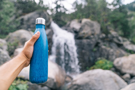 Sustainable and reusable water bottle. Hand holding a blue Eco Friendly Water Bottle. Goodbye to single use plastic bottles. Plastic free and zero waste. Sustainable life.の写真素材