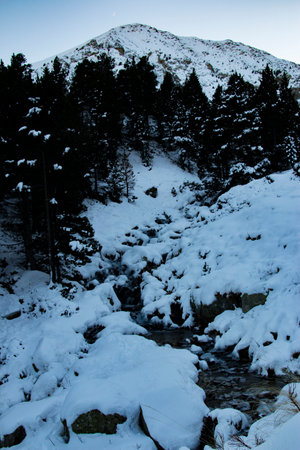 Stream in a calm mountainous landscape just snowed in winter. Peaceful, calm. Vacation, nature, wintry, hiking and cold concept. Vertical photo.の写真素材