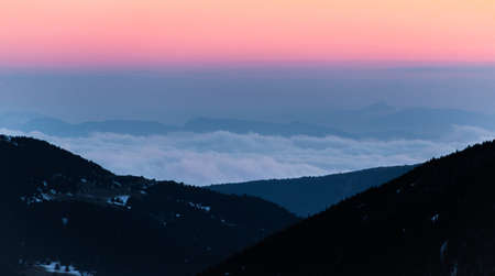 Snowy mountains ranges at sunrise or sunset. Calm and relaxing nature mountainous natural scenery. Nature background landscape with orange and warm colors in the mountains at dusk.の写真素材