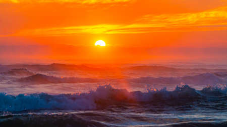 Sea landscape on sunset or sunrise with ocean waves and orange colorful clouds in sky. Concept of vacation on beach, free time, travel, summer, disconnecting from routine and relaxing.の写真素材