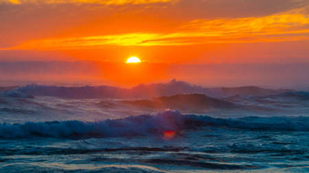 Sea landscape on sunset or sunrise with ocean waves and orange colorful clouds in sky. Concept of vacation on beach, free time, travel, summer, disconnecting from routine and relaxing.の写真素材